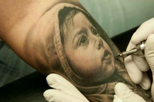 Tatuaggio in 3D del volto di un bambino paffuto. L'effetto è meraviglioso