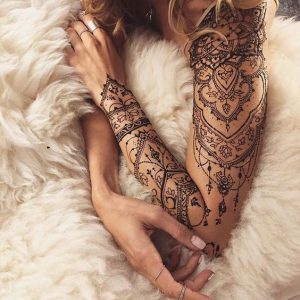 Affascinante tatuaggio realizzato con l'henne, che riempie l'intero braccio di una giovane donna.