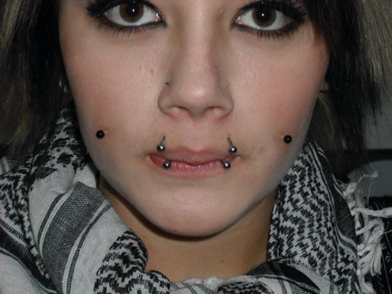 Diversi piercing sulla bocca.