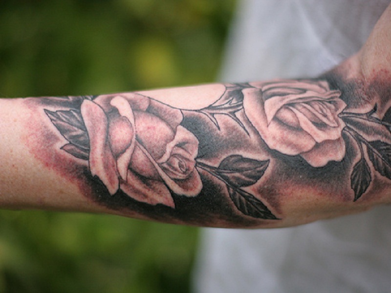 Romantiche rose tatuate sul braccio di un uomo,