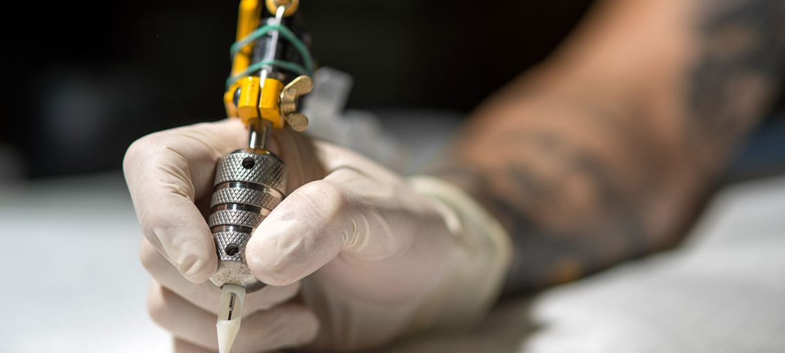 Dettaglio di un tatuatore che indossa guanti a notma